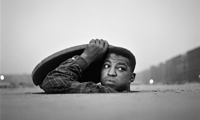 Gordon Parks photo of a young man coming out of a storm grate